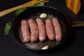 Raw meat sausages in a frying pan on a black background. Royalty Free Stock Photo