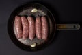 Raw meat sausages in a frying pan on a black background. Royalty Free Stock Photo