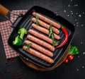 Raw meat sausages on a square grill pan, with herbs and spices Royalty Free Stock Photo