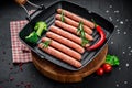 Raw meat sausages on a square grill pan, with herbs and spices Royalty Free Stock Photo