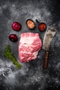 Raw meat, with ingredients and herbs , with old butcher cleaver knife, on black dark stone table background, top view flat lay, Royalty Free Stock Photo