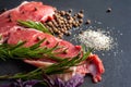 Raw meat with spices. Closeup slices of fresh raw meat with salt, spices and herbs on a black slate stone plate. Preparing and Royalty Free Stock Photo