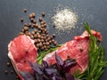 Raw meat with spices. Top view slices of fresh raw meat with salt, spices and herbs on a black slate stone plate. Preparing and Royalty Free Stock Photo