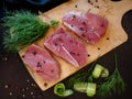 Raw meat, steak on a wooden Board. Spices, dill, peppers and roll of cucumber. Ready for cooking and roasting. Top view. Royalty Free Stock Photo