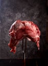 Raw meat stuck on a big fork on a black background
