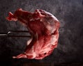 Raw meat stuck on a big fork on a black background