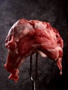 Raw meat stuck on a big fork on a black background