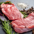 Raw meat. Two slices of fresh raw meat, salt, pepper and rosemary on a black slate stone plate. Preparing and marinating barbecue Royalty Free Stock Photo