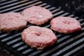 Raw meatballs for burgers are fried on grill. Meat is roasting on BBQ grill outdoor. Heat and smoke dissipate over barbecue