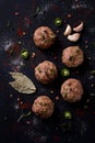 Raw meatballs, with micro greenery, with spices , on a black background , top view, homemade, no people,