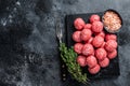 Raw meatballs from minced beef and pork meat with thyme. Wooden background. Top view. Copy space