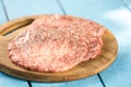 Raw minced meat burgers on the wooden round kitchen board Royalty Free Stock Photo