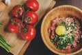 Raw minced meat with egg, herbs and fresh tomatoes on wooden table. Ingredients for cooking meat balls or loaf Royalty Free Stock Photo