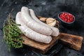 Raw Munich white sausage weisswurst on wooden board. Black background. Top view