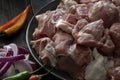 Raw mutton cut into medium pieces, laid on a plate, surrounded by red onions and chili peppers Royalty Free Stock Photo