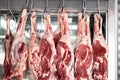 Raw mutton or lamb legs hanging on butcher hooks Royalty Free Stock Photo