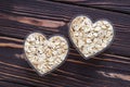 Raw, oat-flakes on dark wood board background. Dry uncooked cereal in two bowl at heart shaped Royalty Free Stock Photo