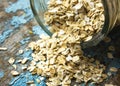 Raw oatmeal is scattered on the desk of the bank in which the oat flakes are stored. blue background in the style of Shabby Chic. Royalty Free Stock Photo