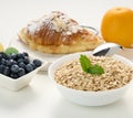 Raw oatmeal in white ceramic plate, blueberry, orange, on white table