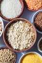 Raw oatmeal in a wooden bowl. Various dry cereals and legumes in white and wooden bowls, white marble background. Vegan protein Royalty Free Stock Photo