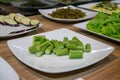 Raw Okra, Zucchini, Lettuce and Pickled Water Spinach on White Plates at a Buffet in a Restaurant