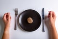 Raw one Jersey cow mushroom in a black plate and a knife and fork nearby on a white background top view. Human hands Royalty Free Stock Photo