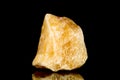 Raw orange calcite mineral stone in front of black background