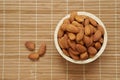 Raw organic almonds in brown wooden bowl placed on brown wooden mat, top view. Royalty Free Stock Photo