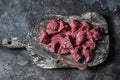 Raw organic beef fillet meat pieces on wooden rustic cutting board on dark background, top view. Food ingredients