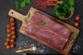 Raw organic marbled beef with spices on a wooden cutting board on a black slate, stone or concrete background Royalty Free Stock Photo