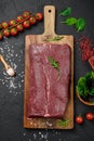 Raw organic marbled beef with spices on a wooden cutting board on a black slate, stone or concrete background Royalty Free Stock Photo