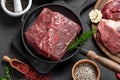 Raw organic marbled beef with spices on a wooden cutting board on a black slate, stone or concrete background Royalty Free Stock Photo