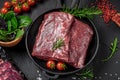 Raw organic marbled beef with spices on a wooden cutting board on a black slate, stone or concrete background Royalty Free Stock Photo