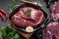 Raw organic marbled beef with spices on a wooden cutting board on a black slate, stone or concrete background Royalty Free Stock Photo