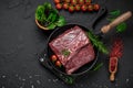 Raw organic marbled beef with spices on a wooden cutting board on a black slate, stone or concrete background Royalty Free Stock Photo
