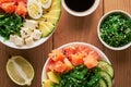 Raw Organic Poke Bowl with rice, avocado, salmon, mango, cucumbers, chuka salad, quail eggs, sweet onions with soy sauce and chuka Royalty Free Stock Photo