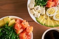 Raw Organic Poke Bowl with rice, avocado, salmon, mango, cucumbers, chuka salad, quail eggs, sweet onions with soy sauce two Royalty Free Stock Photo