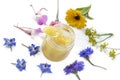 Raw organic royal jelly in a small bottle with litte spoon on small bottle surrounded by flowers on old white background