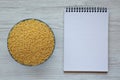 Raw Organic Stelline Pasta in a Bowl, blank notepad on a white wooden background, top view. Flat lay, overhead, from above. Copy Royalty Free Stock Photo