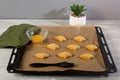 Raw oriental cookies on a baking sheet with a green napkin, egg yolk and acrylic brush