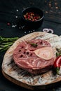 Raw Ossobuko steak marble meat with herbs and spices on dark background. vertical image. top view. place for text