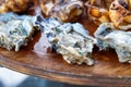 Raw oysters on seafood wooden plate. Close up of charcuterie platter board with oyster, grilled squid, shrimp, fish in Royalty Free Stock Photo