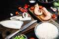 Raw paella ingredients on black wooden table