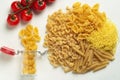 Raw pasta of different types durum wheat several different glass jar with cherry tomatoes top view