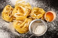 Raw pasta with flour and broken egg on black background Royalty Free Stock Photo