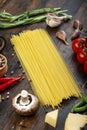 Raw pasta with fresh tomatoes  peppers  asparagus beans  spices and cheese on a wooden table Royalty Free Stock Photo