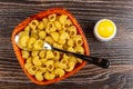 Raw pasta lumache, spoon in bowl, salt shaker on wooden table. Top view