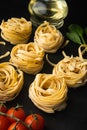 Raw pasta tagliatelle with fresh tomatoes and herbs, on black stone background Royalty Free Stock Photo