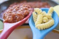 Raw pasta and tomato sauce on two plastic ladles Royalty Free Stock Photo