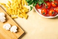 Raw pasta, tomatoes, mushrooms, cutting board, parsley on wooden background, top view. copy space Royalty Free Stock Photo